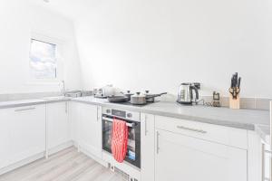 cocina con armarios blancos y fogones en The Residence by Guestz, en Cheltenham