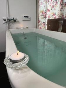 a candle sitting on a glass table in a bath tub at Platina Luxe House in Toyama