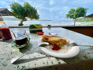 a plate of food on a table with a view of the ocean at Harus Damai Inn in Lagudri