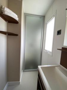 baño blanco con ducha y ventana en Camping Rondinara, en Bonifacio