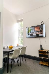 a dining room with a table and chairs and a tv on the wall at Stylish 2 Bedroom Ensuite Flat in Birmingham in Birmingham