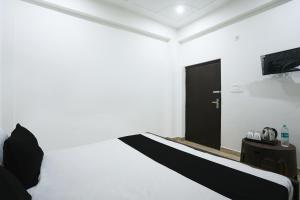 a white room with a bed and a black door at OYO Royal Residency in Agra