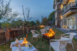 patio ze stołami i krzesłami oraz miejscem na ognisko w obiekcie StayVista at The Mansion w mieście Kasauli