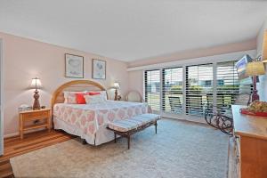 a bedroom with a bed and a large window at Ground floor beachfront with steps to the beach and pool & beach access in New Smyrna Beach