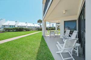 a patio with chairs and tables on a house at Ground floor beachfront with steps to the beach and pool & beach access in New Smyrna Beach