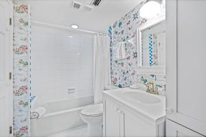 a white bathroom with a toilet and a sink at Ground floor beachfront with steps to the beach and pool & beach access in New Smyrna Beach