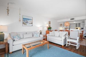 a living room with two white couches and a table at Ground floor beachfront with steps to the beach and pool & beach access in New Smyrna Beach
