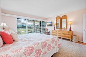 a bedroom with a bed and a dresser and a mirror at Ground floor beachfront with steps to the beach and pool & beach access in New Smyrna Beach