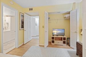 a living room with yellow walls and a television at Ground floor beachfront with steps to the beach and pool & beach access in New Smyrna Beach
