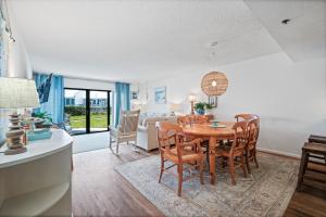 a dining room and living room with a table and chairs at Ground floor beachfront with steps to the beach and pool & beach access in New Smyrna Beach