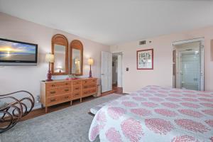 a bedroom with a bed and a dresser and a mirror at Ground floor beachfront with steps to the beach and pool & beach access in New Smyrna Beach