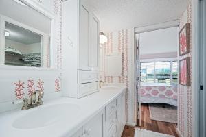 a white bathroom with a sink and a mirror at Ground floor beachfront with steps to the beach and pool & beach access in New Smyrna Beach