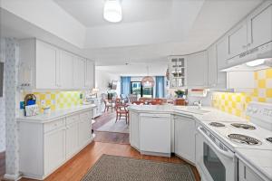 a kitchen with white cabinets and yellow squares on the wall at Ground floor beachfront with steps to the beach and pool & beach access in New Smyrna Beach