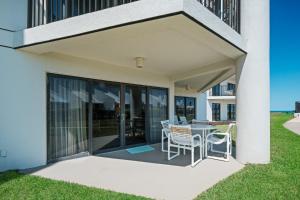 a patio with chairs and a table on the side of a house at Ground floor beachfront with steps to the beach and pool & beach access in New Smyrna Beach