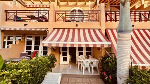 Un edificio con una mesa y sillas y una palmera. en Click&Guest - Dunes Breeze in Maspalomas, en San Bartolomé