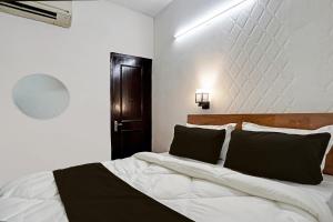 a bedroom with a large white bed with black pillows at OYO Kiiza Stay House in New Delhi