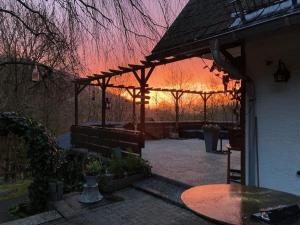 a sunset in a backyard with a wooden pergola at Gasthof Walhalja in Schmallenberg