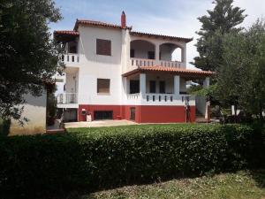 een groot wit en rood huis met een tuin bij Family Villa Dora in Zakharo