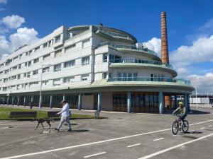 een vrouw die een hond uitlaat voor een gebouw bij Poniente Beach in Gijón