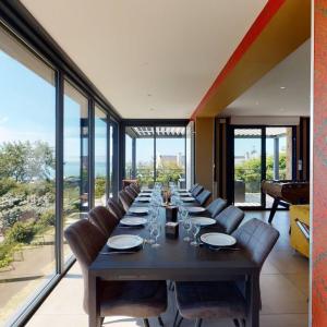 a long dining room with a long table and chairs at Casa Antoine 15pers : vue mer, 10 min à pied plage in Donville-les-Bains
