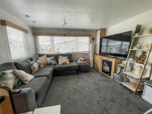 a living room with a couch and a flat screen tv at Lovely 8 Berth Caravan With Wifi At Dovercourt Holiday Park Ref 44002d in Great Oakley