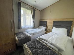 a bedroom with two beds and a window at Beautiful Caravan With Decking And Wifi At Azure Sea, Suffolk Ref 32025az in Lowestoft