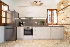 La cuisine est équipée de placards blancs et d'un réfrigérateur en acier inoxydable. dans l'établissement Alexandros, à Megísti