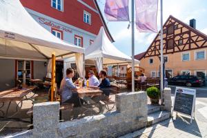 a group of people sitting at a table in front of a building at Seebauer-Hotel Die Ente von Wassertrüdingen in Wassertrüdingen