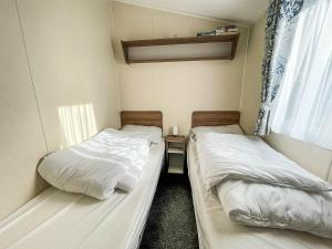 two beds in a small room with a window at Lovely 6 Berth, Dog Friendly Caravan For Hire In Norfolk Ref 50011ae in Great Yarmouth