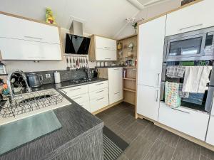 a kitchen with white cabinets and a refrigerator at Beautiful 6 Berth Caravan With Decking At Dovercourt Park, Essex Ref 44009g in Great Oakley