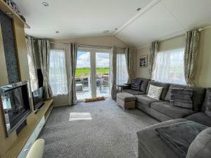a living room with a couch and a flat screen tv at Beautiful 6 Berth Caravan With Decking At Dovercourt Park, Essex Ref 44009g in Great Oakley