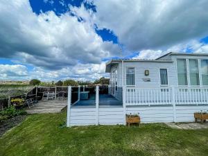 a white house with a porch and a yard at Beautiful 6 Berth Caravan With Decking At Dovercourt Park, Essex Ref 44009g in Great Oakley