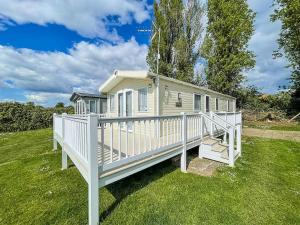 a small white house with a white porch at Gorgeous 6 Berth Caravan With Decking Area, Dovercourt Holiday Park Ref 44010af in Great Oakley