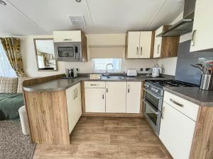 a kitchen with white cabinets and a stove top oven at Gorgeous 6 Berth Caravan With Decking Area, Dovercourt Holiday Park Ref 44010af in Great Oakley