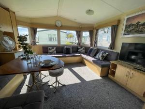 a living room with a couch and a table at Great Caravan At Valley Farm Holiday Park, Essex Ref 46583v in Great Clacton