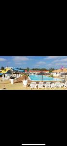 a view of a pool with white chairs and a resort at Mobil home 6/8 personnes aux Mathes / La Palmyre in Les Mathes