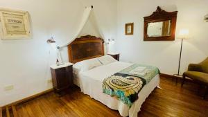1 dormitorio con 1 cama grande y 1 silla en Antigua Casona Bed & Breakfast en San Antonio de Areco