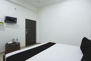 a bedroom with a white bed and a black door at OYO Royal Residency in Agra