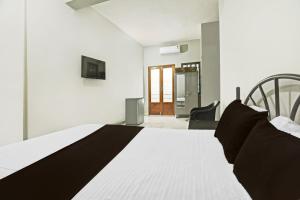 1 dormitorio con 1 cama blanca y 1 silla en OYO Pravin Guest House, en Goa