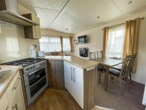 a small kitchen with a stove and a table at Gorgeous 6 Berth Caravan With Large Decking Area, Essex Ref 44009f in Great Oakley