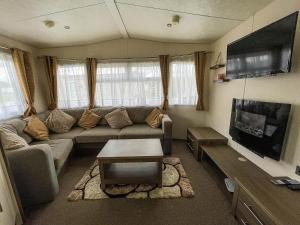 a living room with a couch and a flat screen tv at Gorgeous 6 Berth Caravan With Large Decking Area, Essex Ref 44009f in Great Oakley