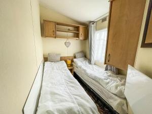 a small room with two beds and a window at Great 8 Berth Caravan With Wifi At Dovercourt Holiday Park In Essex Ref 44003c in Great Oakley