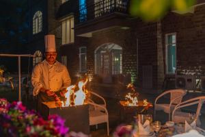 カソーリにあるThe Mansion - A Magnificent Villaの火の横に立つ料理人帽子の男