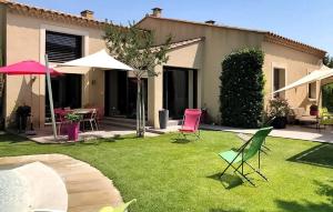 a yard with chairs and tables and an umbrella at La Villa De Sévigné in Rognonas