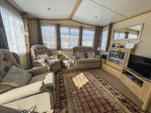 a living room with a couch and a tv at Ref 40035nd - Superb Caravan With Decking Free Wifi At North Denes Holiday Park in Lowestoft