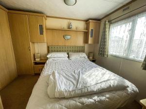 a bedroom with a bed with white sheets and a window at Ref 40035nd - Superb Caravan With Decking Free Wifi At North Denes Holiday Park in Lowestoft