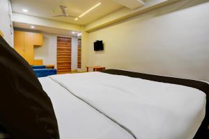 een slaapkamer met een wit bed en een televisie bij OYO Hotel The Park View Rooms in Surat
