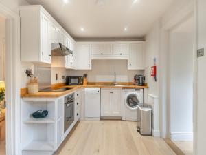 a kitchen with white cabinets and a washer and dryer at Gardeners Cottage in Overstrand