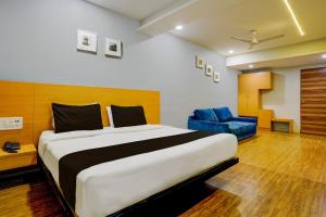 een slaapkamer met een groot bed en een blauwe stoel bij OYO Hotel The Park View Rooms in Surat