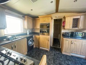 a kitchen with wooden cabinets and a sink at Great 4 Berth Caravan For Hire In Suffolk At North Denes, Ref 40149nd in Lowestoft